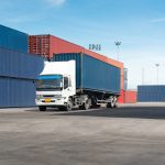 truck with cargo container on road in shipping yard or dock yard against sunrise